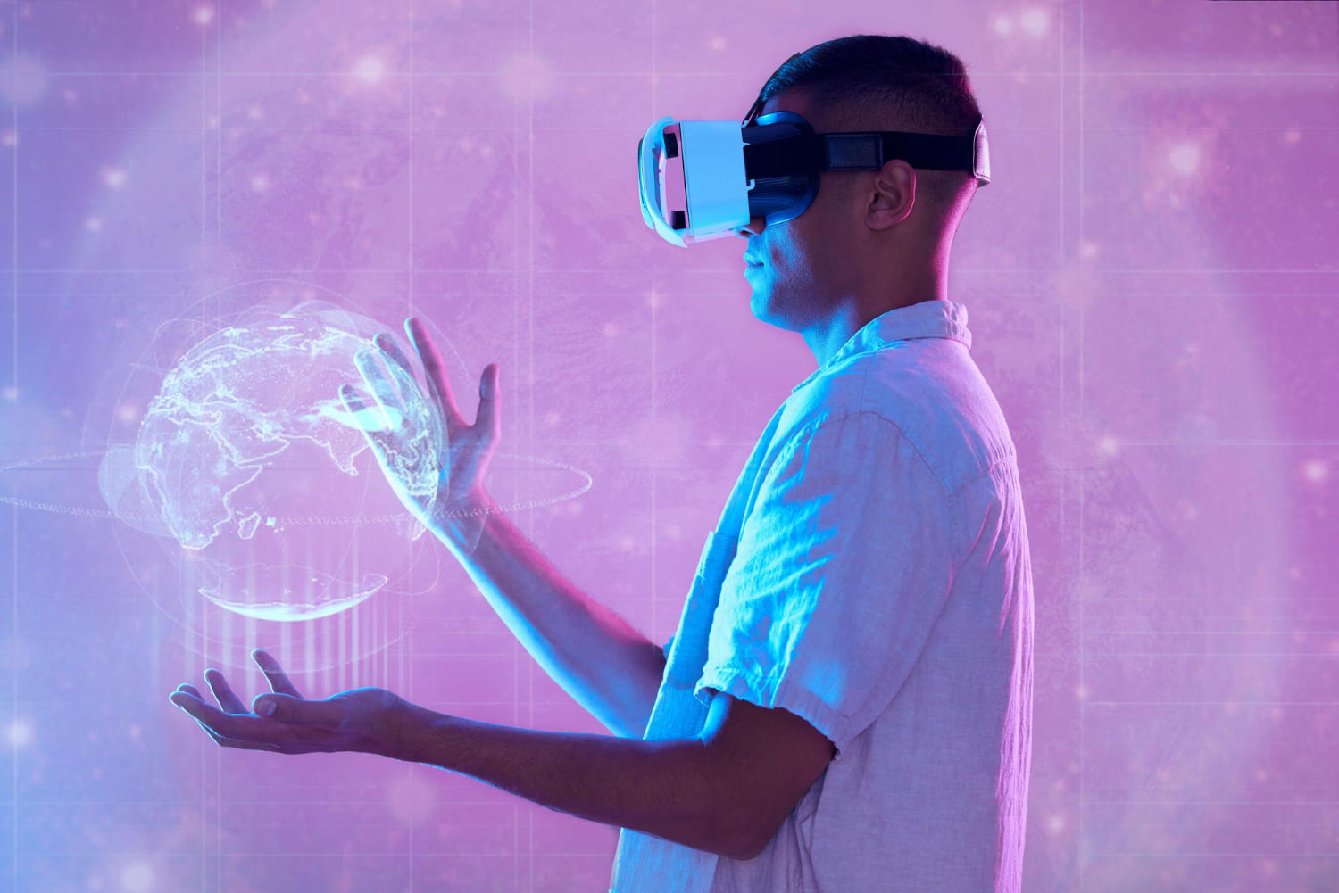 Person wearing a VR headset gesturing with a raised hand at a desk with editing monitors